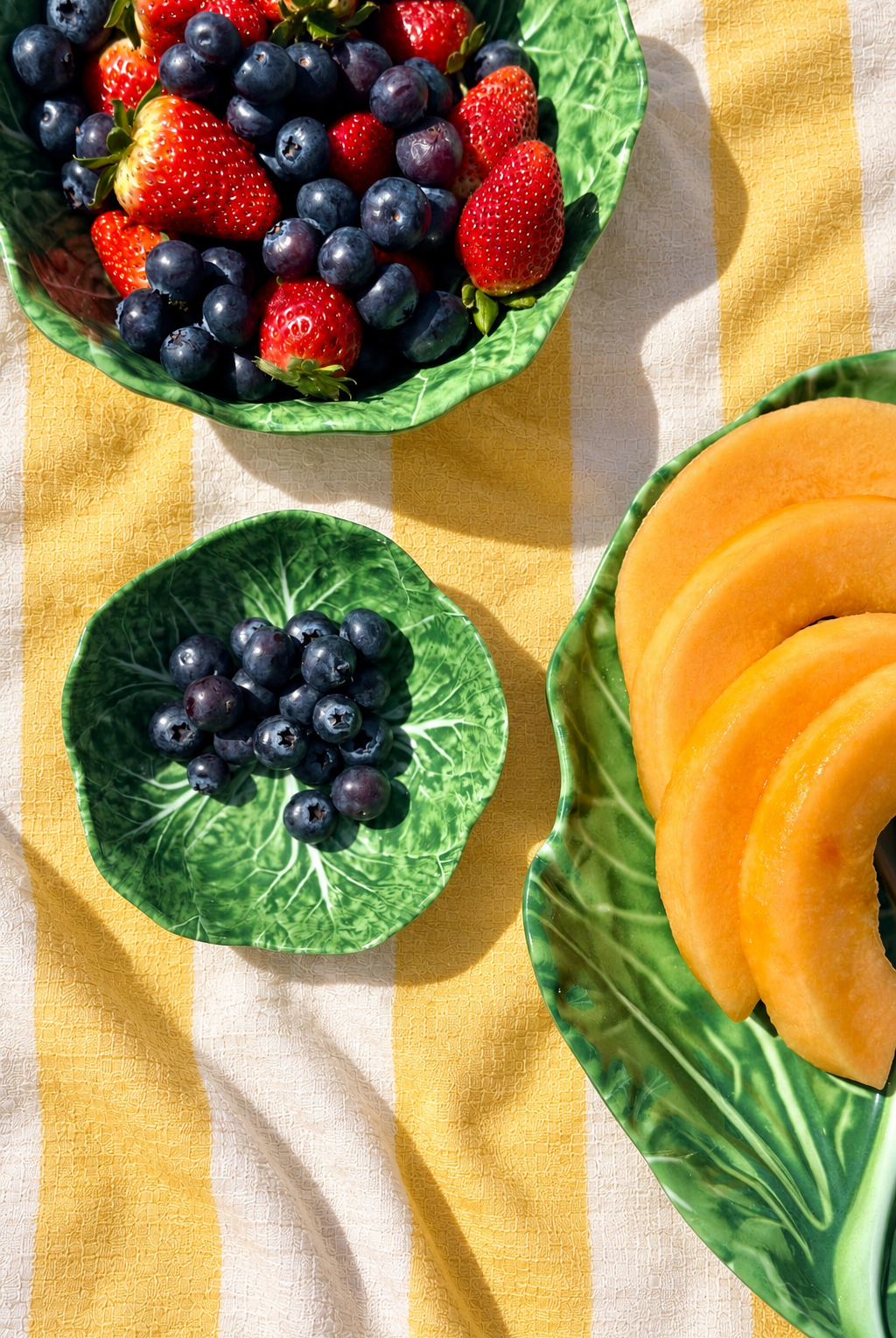 Green Baby Bowls – Cabbage Melamine styled with berries and melon on yellow and white striped tablecloth