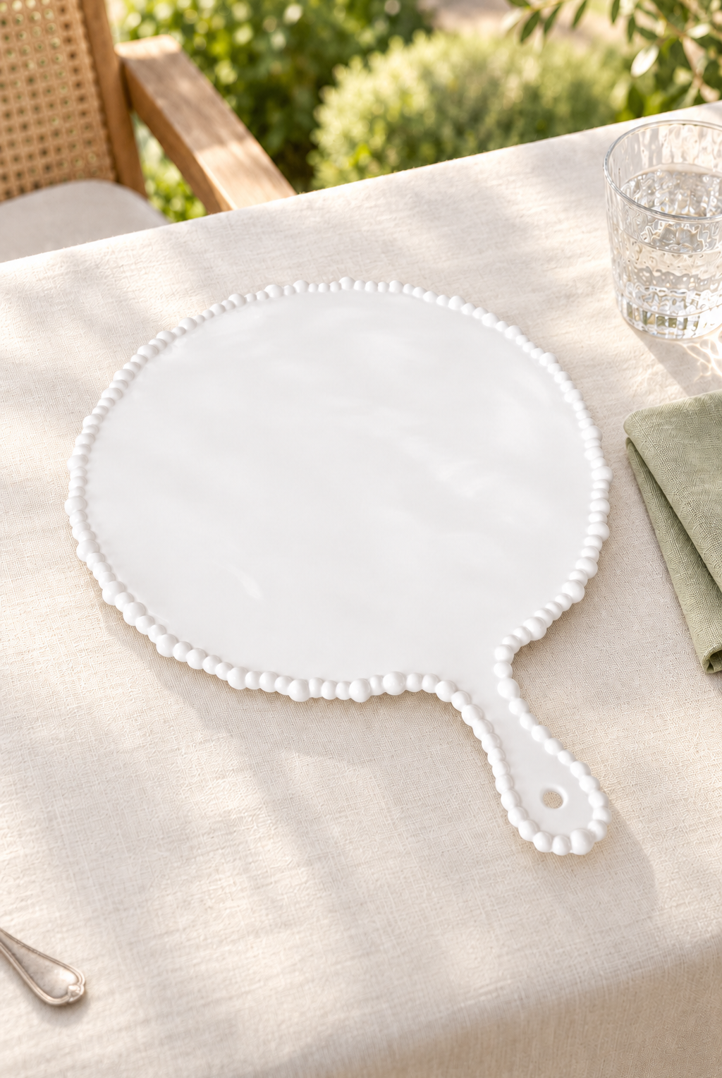 White Pearl Melamine round platter with handle styled outdoors with green linen