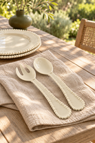 Sand Pearl salad servers on linen with matching plates outdoors