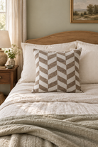 Chevron Weave Cushion in natural and white, styled on a linen bed with an oak headboard