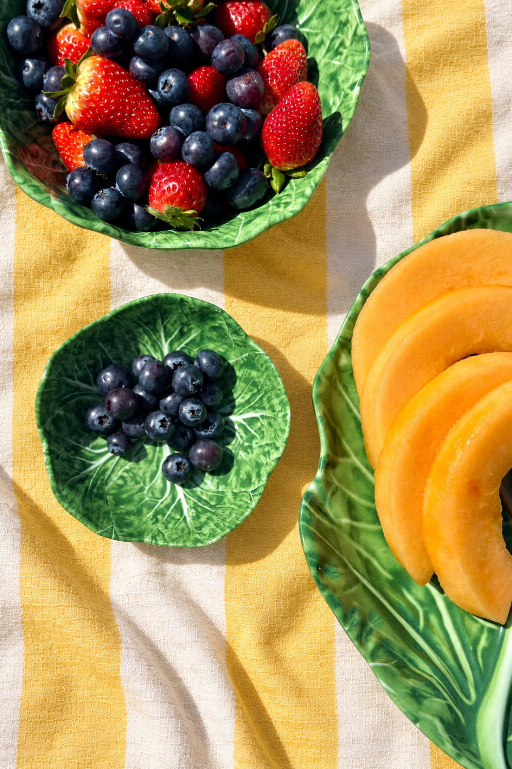 Green Baby Bowls – Cabbage Melamine styled with berries and melon on yellow and white striped tablecloth
