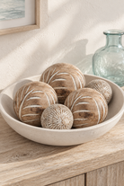 Spruce 10 centimetre carved wooden balls with smaller Mandalay companions in a shallow bowl