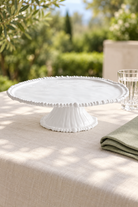 White Pearl Melamine cake stand, empty, styled outdoors with green linen