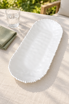 White Pearl Melamine long platter styled outdoors with green linen