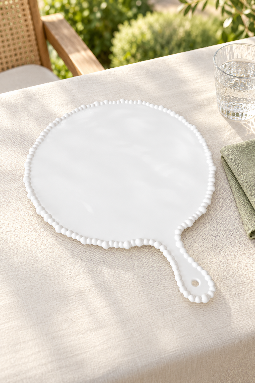 White Pearl Melamine round platter with handle styled outdoors with green linen, alternate view