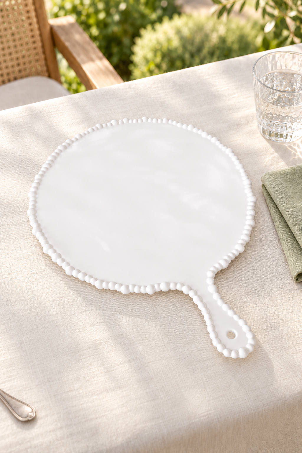 White Pearl Melamine round platter with handle styled outdoors with green linen